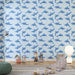 Une chambre d'enfant avec un papier peint illustrant des dauphins bleus sur fond bleu clair, créant une ambiance ludique et marine.