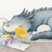 Une chambre d'enfant avec un papier peint illustrant un dragon endormi aux teintes douces de bleu et de gris, créant une atmosphère rêveuse et apaisante.