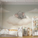 Une chambre d'enfant avec un papier peint illustrant un éléphant endormi sur un nuage, créant une ambiance douce et rêveuse.