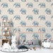 Une chambre d'enfant avec un papier peint illustré d'éléphants bleus sur fond beige, créant une ambiance douce et ludique.