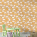 Une chambre d'enfant avec un papier peint joyeux représentant des soleils souriants et des nuages sur un fond beige, créant une atmosphère ludique et chaleureuse.
