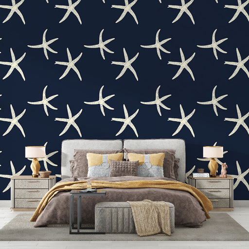 Une chambre élégante avec un papier peint marine représentant des étoiles de mer blanches sur fond bleu nuit, créant une ambiance apaisante et estivale.