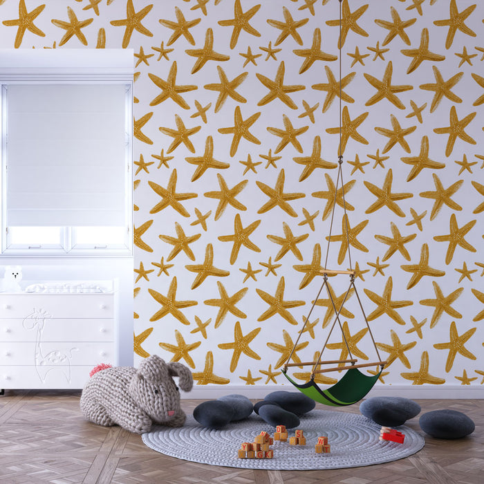 Une chambre d'enfant avec un papier peint représentant des étoiles de mer dorées sur fond blanc, créant une ambiance joyeuse et marine.