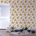 Une chambre d'enfant avec un papier peint représentant des étoiles de mer dorées sur fond blanc, créant une ambiance joyeuse et marine.