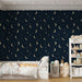 Une chambre d'enfant avec un papier peint bleu nuit orné de lunes dorées et d'étoiles, créant une atmosphère rêveuse et apaisante.