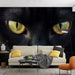 Un salon contemporain avec un papier peint représentant de grands yeux de chat noir aux reflets dorés, créant une atmosphère intrigante et captivante.