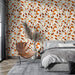 Une chambre moderne avec un papier peint aux motifs de feuilles dans des teintes chaudes d'orange et de beige, créant une atmosphère accueillante et naturelle.