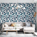 Un salon lumineux avec un papier peint aux motifs de feuillage bleu marine et turquoise sur fond blanc, créant une ambiance fraîche et naturelle.