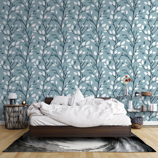Une chambre apaisante avec un papier peint aux motifs de branches et feuilles blanches sur fond bleu, créant une atmosphère naturelle et sereine.