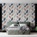 Une chambre moderne avec un papier peint aux motifs de feuilles délicates dans des teintes de bleu, rose et crème, créant une atmosphère apaisante et naturelle.
