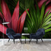 Une pièce moderne avec un papier peint tropical aux grandes feuilles vertes et rouges, créant une atmosphère vivante et énergisante.