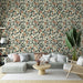 Un salon moderne avec un papier peint floral aux motifs de feuilles vertes et ocres sur fond crème, dégageant une ambiance chaleureuse et naturelle.