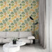 Un salon moderne avec un papier peint aux motifs de feuilles colorées dans des teintes vertes, jaunes et orange, créant une ambiance fraîche et accueillante.
