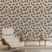 Un salon moderne avec un papier peint beige orné de motifs de branches noires, créant une ambiance naturelle et apaisante.