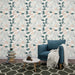 Un salon moderne avec un papier peint floral aux motifs de feuilles vertes et pêche sur fond clair, créant une atmosphère douce et accueillante.