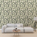 Un salon moderne avec un papier peint aux motifs de feuillage vert et noir sur fond clair, créant une ambiance naturelle et apaisante.