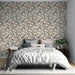 Une chambre élégante avec un papier peint aux motifs de feuilles noires sur fond beige, créant une ambiance apaisante et naturelle.