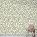 Une pièce moderne avec un papier peint aux motifs de feuillage délicat dans des teintes vertes sur fond crème, créant une atmosphère apaisante et naturelle.
