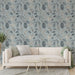 Un salon moderne avec un papier peint aux motifs de feuilles délicates en noir et beige sur fond bleu, créant une ambiance apaisante et naturelle.