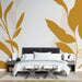Une chambre moderne avec un papier peint aux motifs de grandes feuilles stylisées dans des teintes dorées et neutres, créant une ambiance chaleureuse et apaisante.