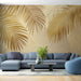 Un salon moderne avec un papier peint aux grandes feuilles dorées sur fond beige, créant une ambiance chaleureuse et tropicale.