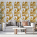 Un salon moderne avec un papier peint aux motifs de grandes feuilles dorées sur fond marbré, créant une ambiance élégante et chaleureuse.