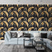 Un salon moderne avec un papier peint tropical aux grandes feuilles dorées et noires sur fond sombre, créant une ambiance élégante et chaleureuse.