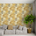Un salon moderne avec un papier peint tropical aux motifs de grandes feuilles dorées et grises sur fond clair, créant une ambiance chaleureuse et accueillante.