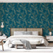 Une chambre élégante avec un papier peint bleu profond orné de motifs de feuilles dorées, créant une atmosphère apaisante et naturelle.