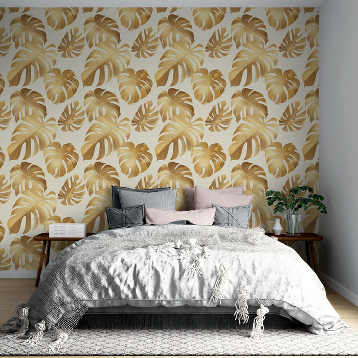 Une chambre élégante avec un papier peint tropical aux grandes feuilles dorées sur fond clair, créant une atmosphère chaleureuse et apaisante.