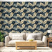 Un salon lumineux avec un papier peint tropical aux grandes feuilles dans des teintes de bleu et beige, créant une atmosphère apaisante et élégante.
