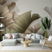 Un salon moderne avec un papier peint représentant de grandes feuilles tropicales aux lignes délicates dans des teintes beige et vert, créant une ambiance naturelle et apaisante.