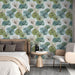 Une chambre élégante avec un papier peint floral aux motifs de grandes feuilles dans des teintes vertes et bleues, créant une atmosphère apaisante et naturelle.