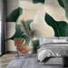 Une chambre moderne avec un papier peint représentant de grandes feuilles vertes et blanches sur fond beige, créant une atmosphère apaisante et naturelle.