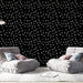 Un salon moderne avec un papier peint noir orné de motifs de feuilles grises, créant une ambiance élégante et contemporaine.