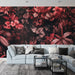 Un salon moderne avec un papier peint tropical aux motifs luxuriants de feuilles rouges et roses sur fond noir, créant une atmosphère chaleureuse et accueillante.