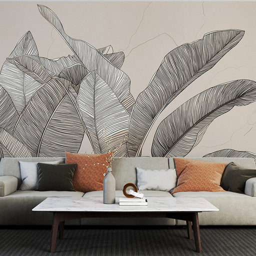 Un salon moderne avec un papier peint représentant de grandes feuilles tropicales en lignes noires sur fond beige, créant une atmosphère élégante et apaisante.