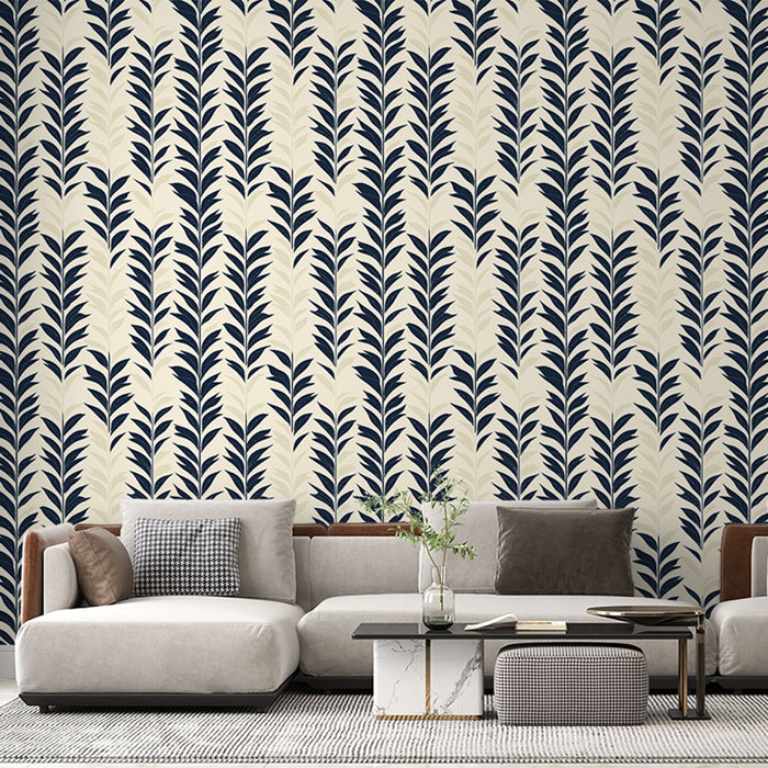Un salon moderne avec un papier peint aux motifs de feuilles bleu marine sur fond crème, créant une ambiance élégante et apaisante.