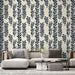Un salon moderne avec un papier peint aux motifs de feuilles bleu marine sur fond crème, créant une ambiance élégante et apaisante.
