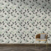 Une pièce moderne avec un papier peint aux motifs de feuilles délicates en noir et vert d'eau sur fond clair, créant une ambiance naturelle et apaisante.