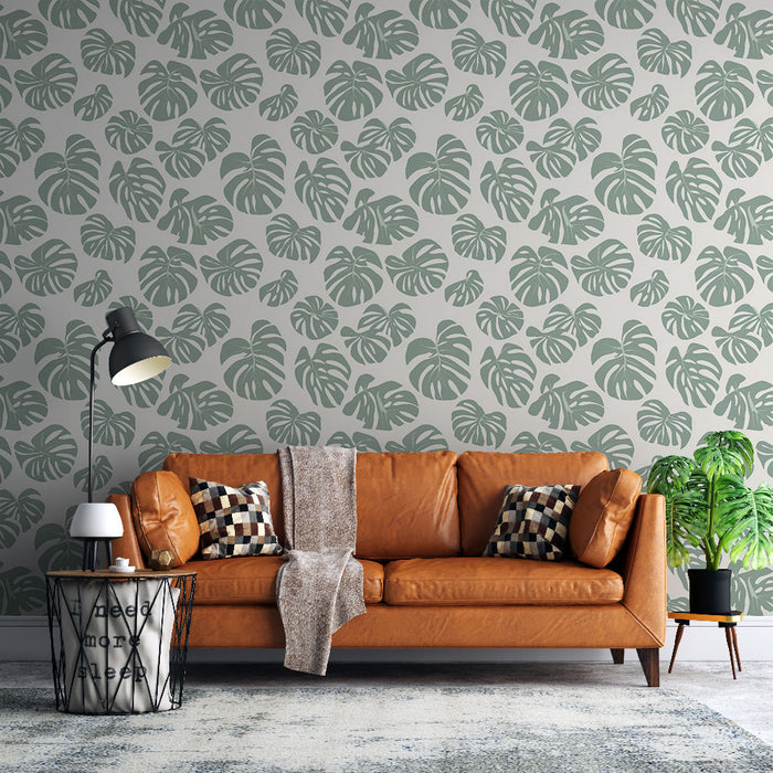 Un salon moderne avec un papier peint tropical vert doux représentant des feuilles de monstera sur fond clair, créant une ambiance chaleureuse et accueillante.