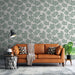 Un salon moderne avec un papier peint tropical vert doux représentant des feuilles de monstera sur fond clair, créant une ambiance chaleureuse et accueillante.