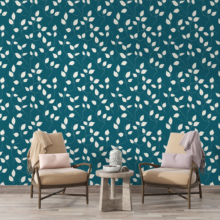 Un salon élégant avec un papier peint aux motifs de feuilles blanches sur fond bleu canard, créant une atmosphère apaisante et naturelle.
