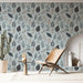 Une pièce lumineuse avec un papier peint aux motifs de feuilles stylisées dans des teintes de bleu, noir et beige, créant une ambiance naturelle et apaisante.