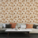 Un salon moderne avec un papier peint aux motifs de feuilles dans des teintes brunes et beiges, créant une atmosphère chaleureuse et naturelle.
