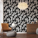 Une pièce moderne avec un papier peint noir orné de motifs de feuilles blanches, créant une ambiance élégante et dynamique.