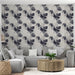 Un salon moderne avec un papier peint tropical aux motifs de grandes feuilles noires et grises sur fond clair, créant une atmosphère élégante et apaisante.