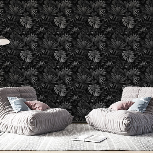 Un salon moderne avec un papier peint tropical noir aux motifs de feuilles exotiques, créant une atmosphère élégante et mystérieuse.