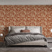 Une chambre élégante avec un papier peint terracotta orné de motifs de feuilles crème, créant une atmosphère chaleureuse et accueillante.