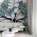 Un salon contemporain avec un papier peint tropical aux grandes feuilles stylisées en noir et vert, créant une ambiance fraîche et apaisante.